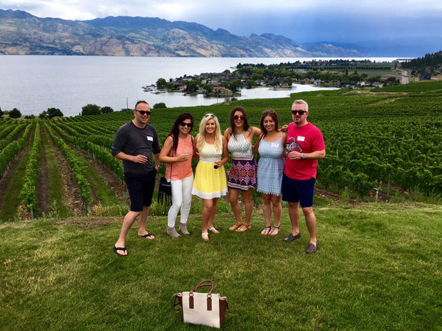 Several women tasting wine with view behind them from Quail's Gate Winery